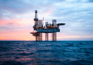 Offshore oil and gas platform at sea during sunset, supported by jack-up legs above the water